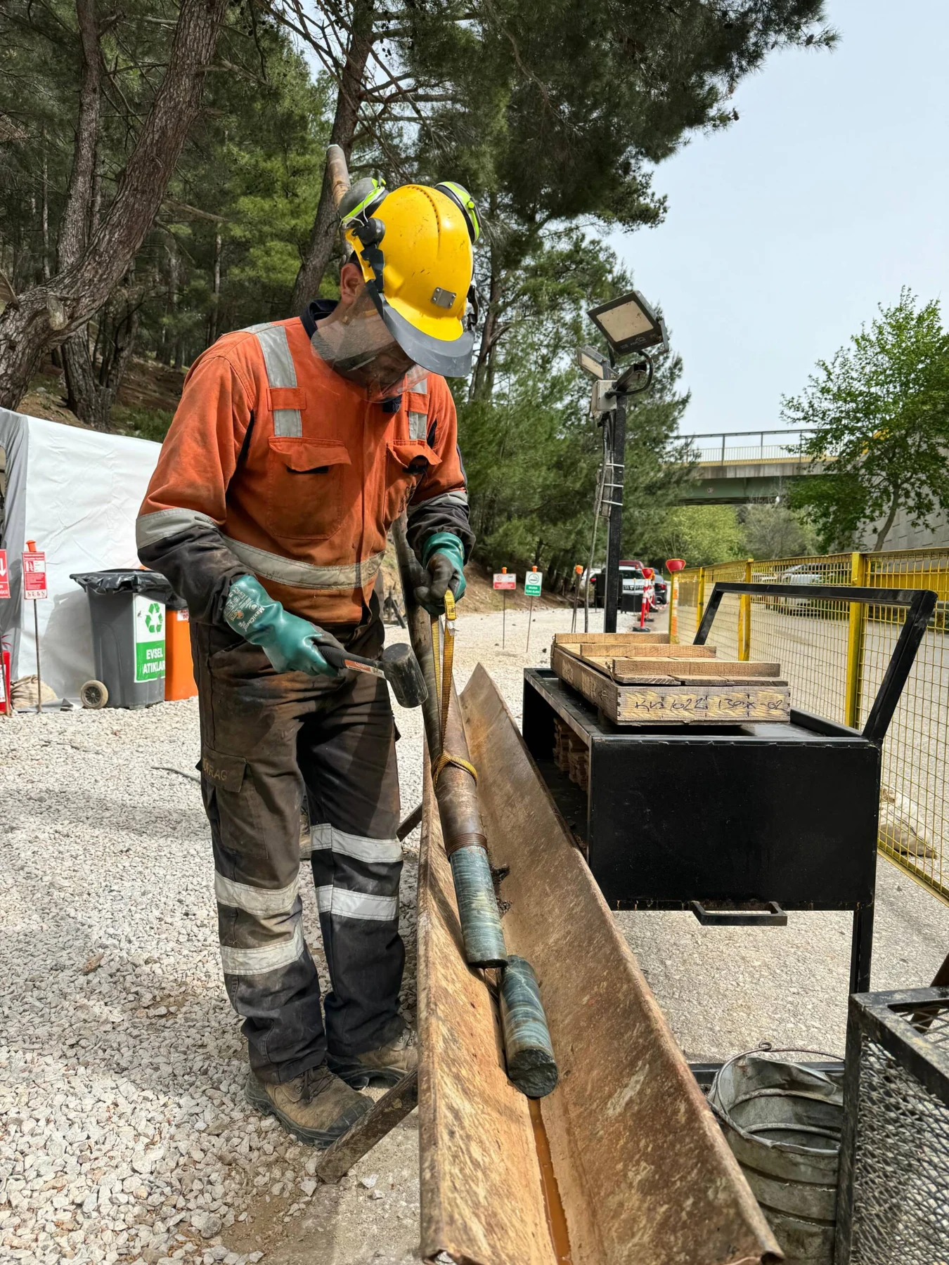 Crew member handling a core barrel beside core trays